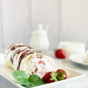 cake-roll-on-a-white-plate-with-strawberries-and-mint-on-the-side