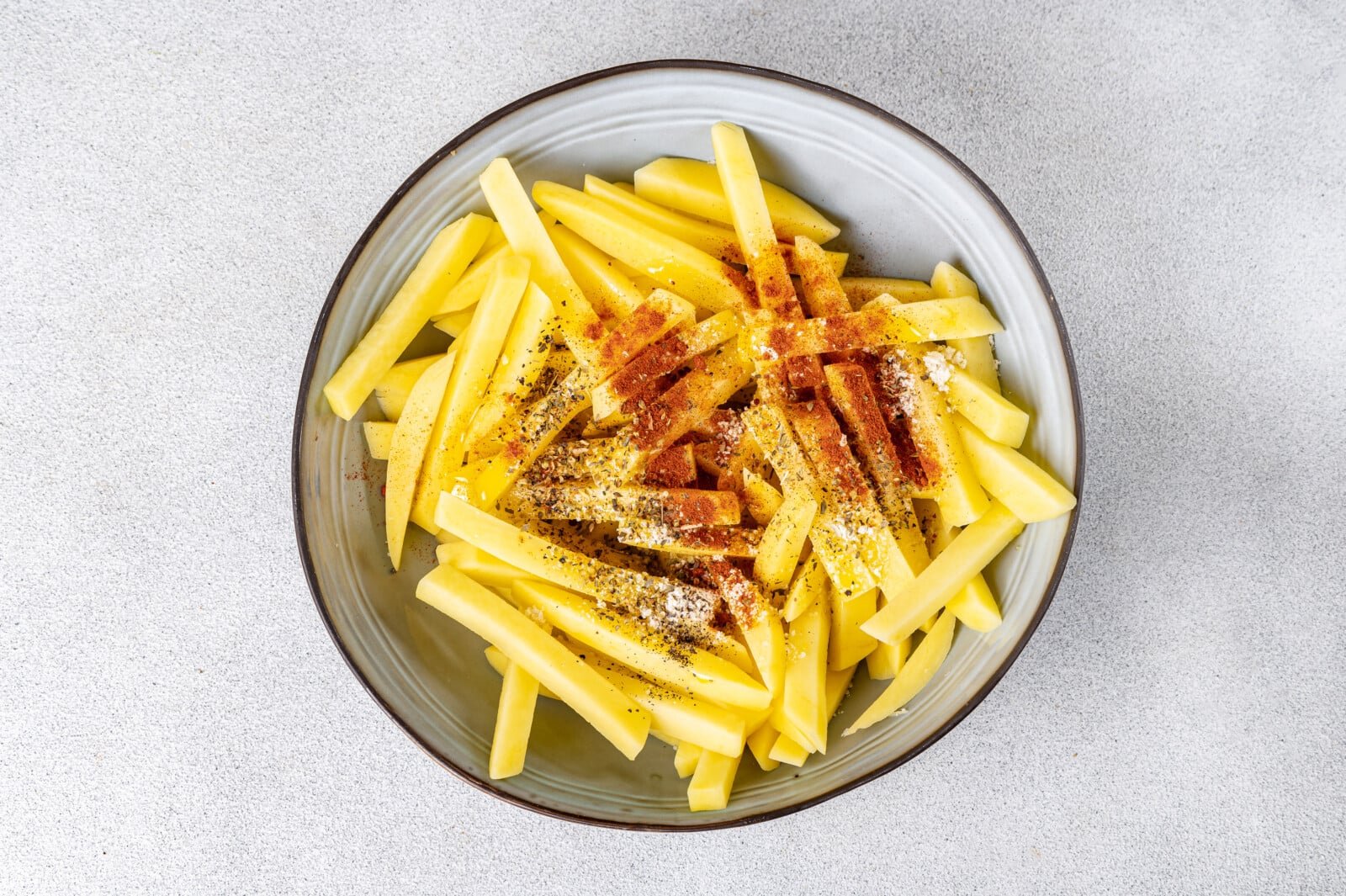 Potatoes with seasoning on top in a bowl.