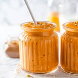 pumpkin pie smoothie in a glass cup with a straw.