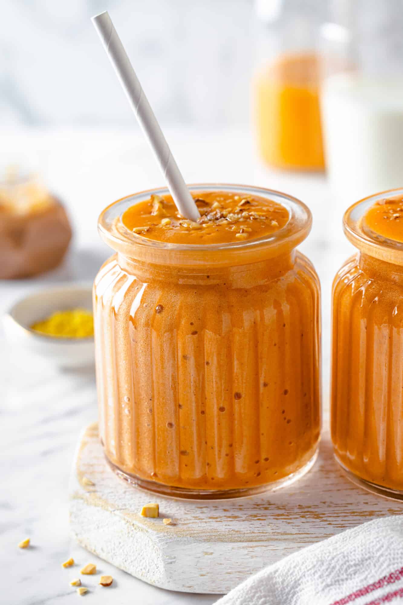 pumpkin pie blended smoothie in two cups with straw. 