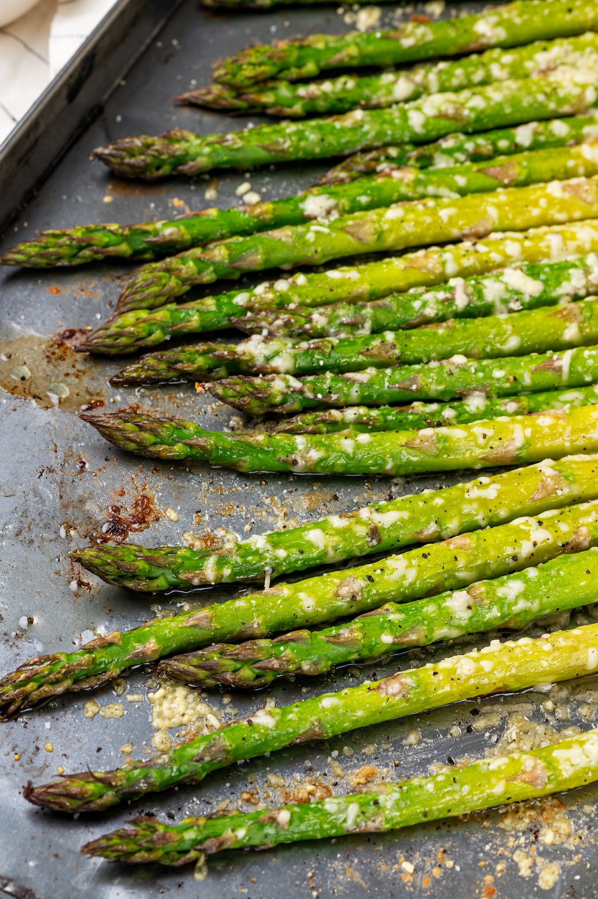 roasted asparagus with spices olive oil and parmesan cheese on a baking sheet.