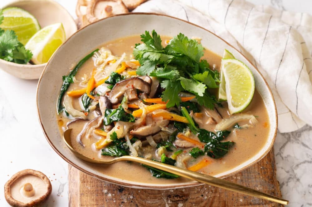Thai coconut soup recipe in a bowl with a lime wedge on the side.