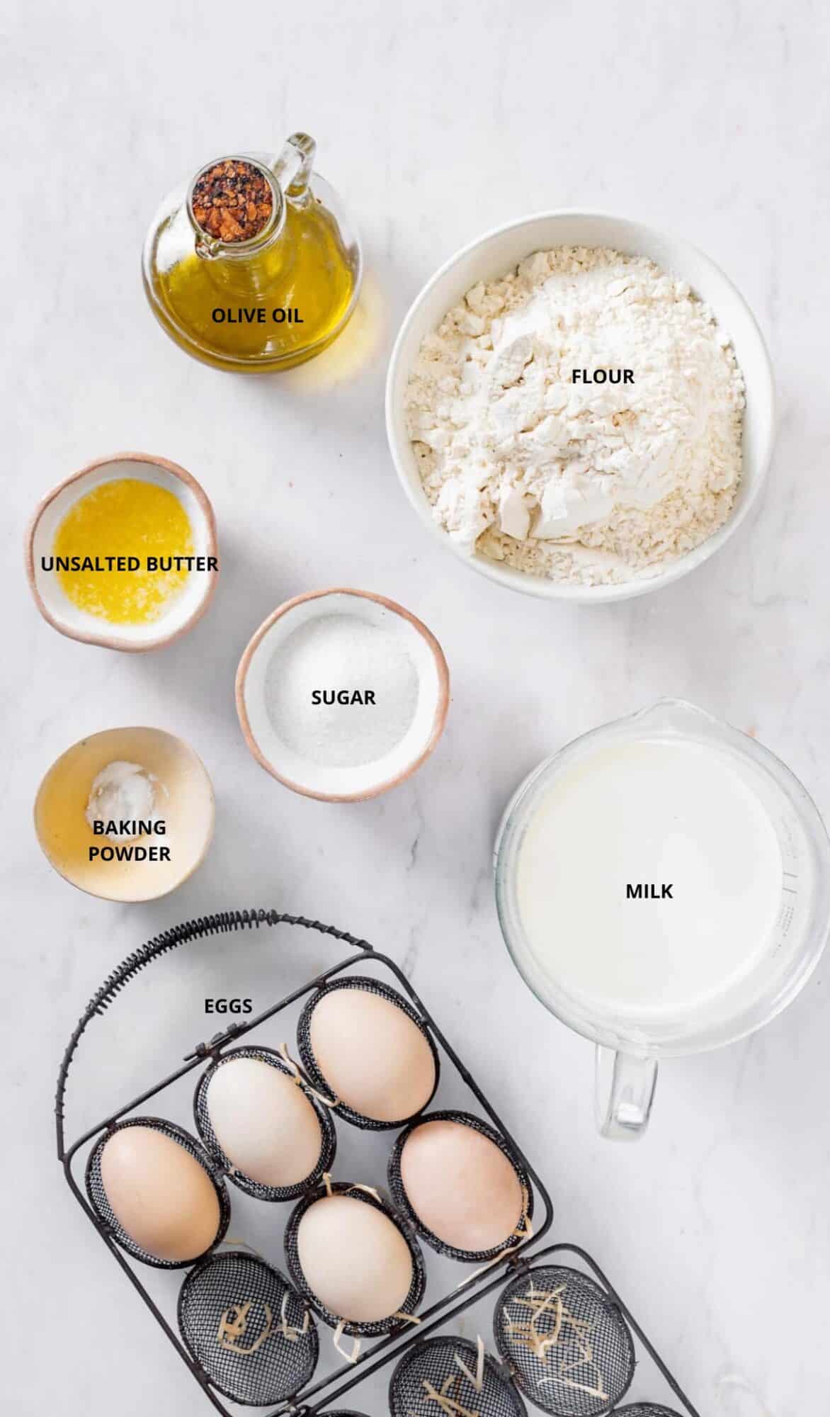 basic crepe recipe ingredients six large eggs bowl of flour four cups of milk olive oil bottle baking powder white sugar in a bowl and melted unsalted butter.
