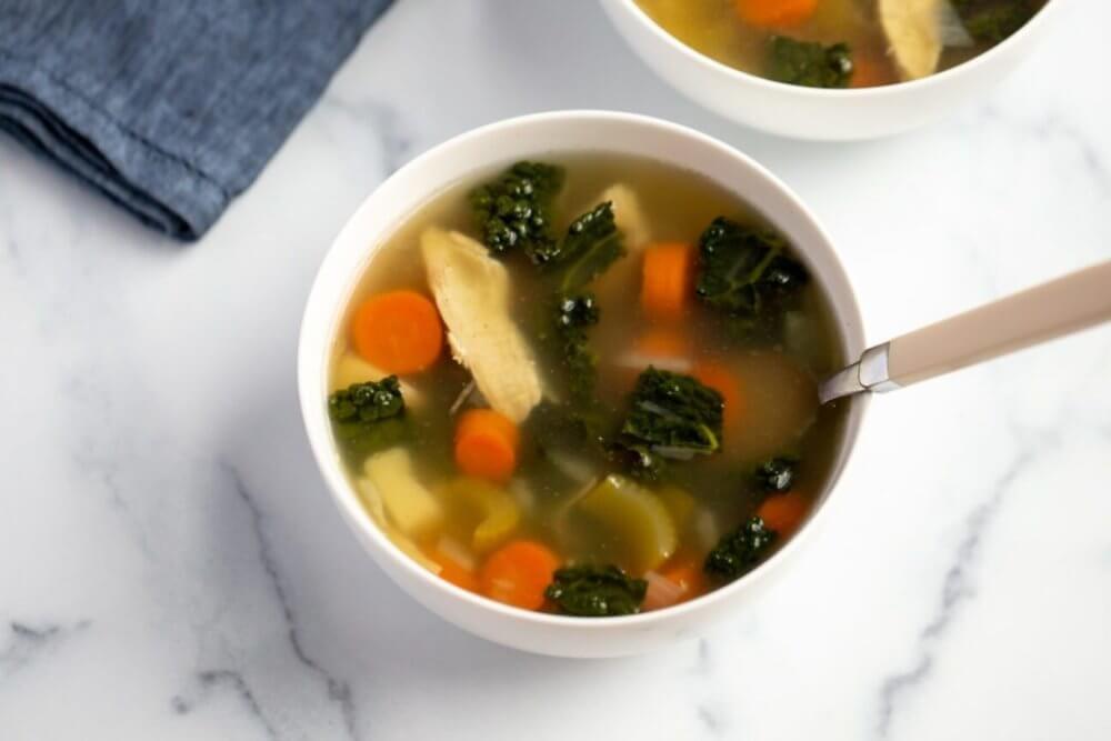 healing chicken vegetable soup in a white bowl.