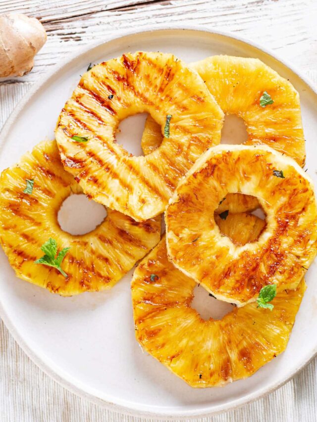 grilled pineapple slices on a white plate.
