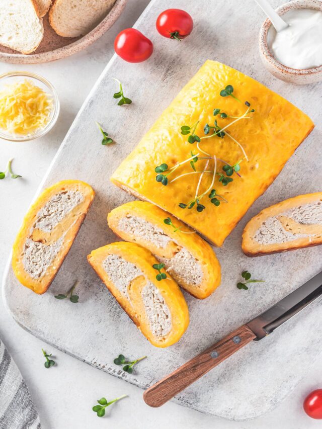 Sliced chicken and cheese roulade on a marble cutting board topped with a sprinkle of micro greens.