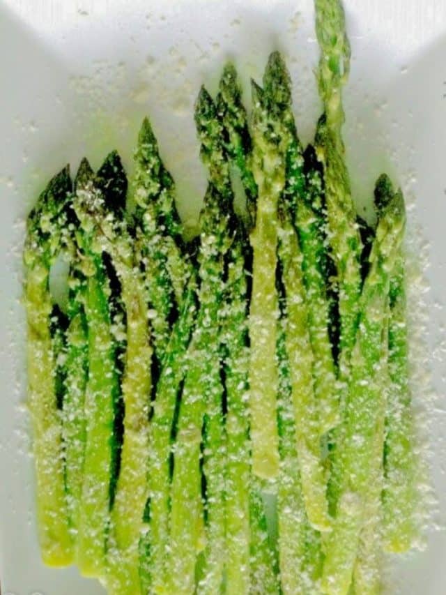 asparagus on a white plate with parmesan on top.