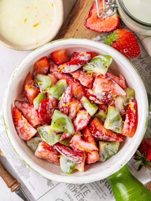 strawberry kiwi salad with yogurt dressing in a white bowl.