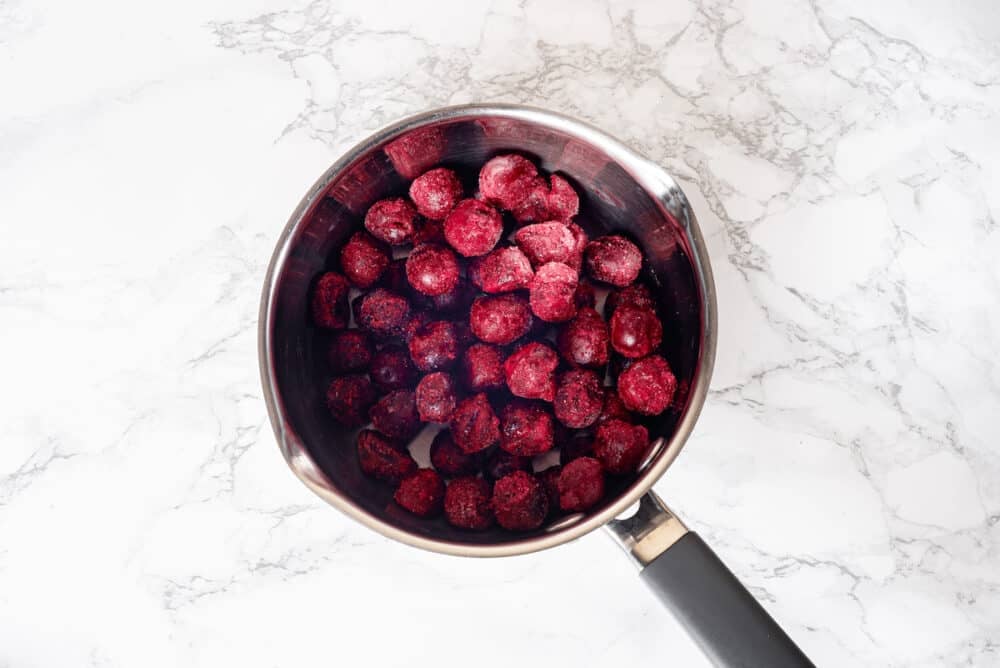 red cherries in a silver small saucepan to cook.