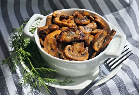 mushroom-side-dish-in-a-white-bowl-on-a-white-plate-with-a-fork-on-a-striped-towel