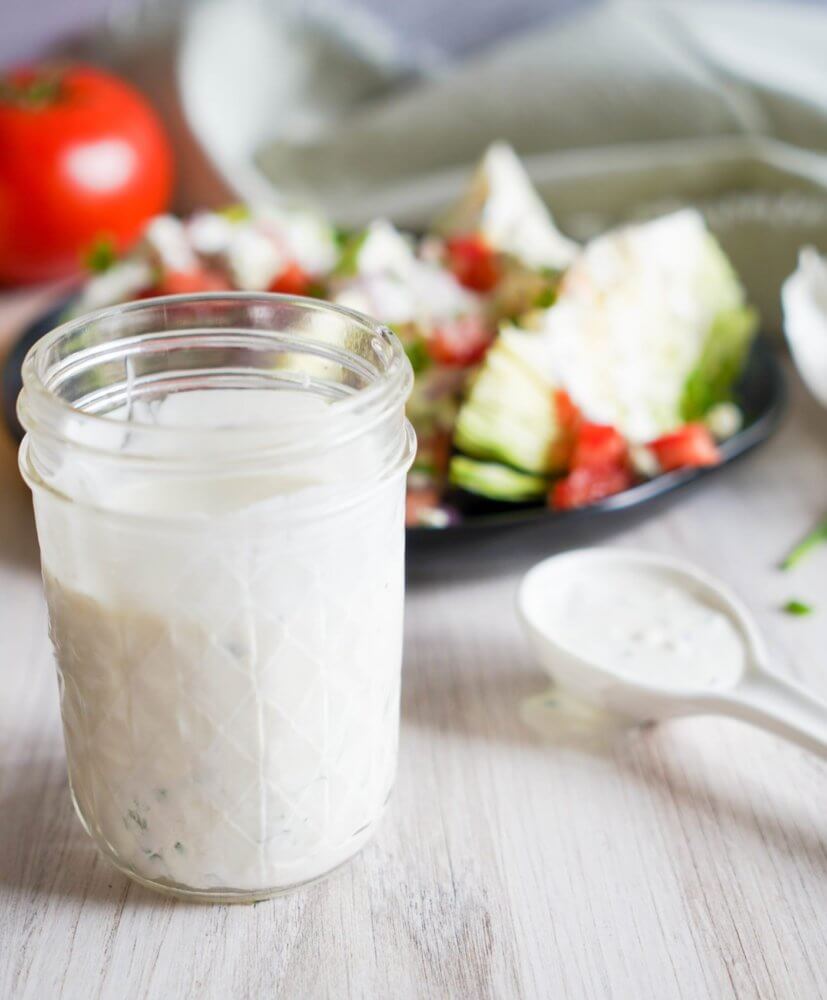ranch-dressing-in-a-jar-with-wedge-salad-in-the-background-on-a-plate-and-a-spoon-with-ranch-in-it