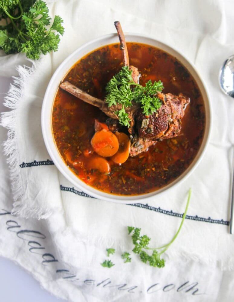 lamb-soup-in-a-white-bowl-with-lamb-and-parsley-on-top-on-a-white-towel