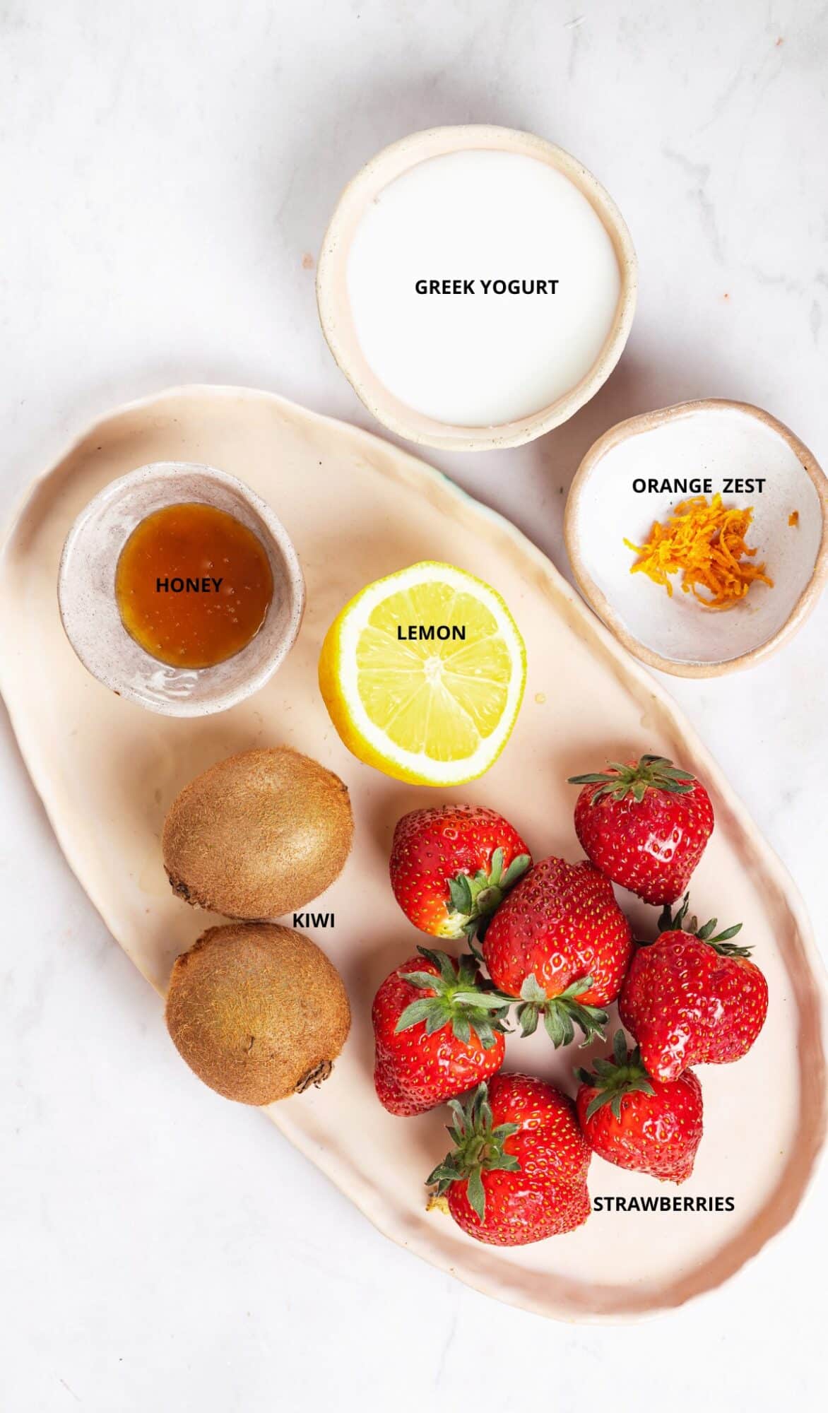 orange zest greek yogurt honey lemon kiwi strawberries on a beige plater and individual bowls.