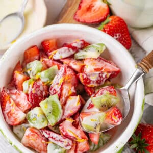 strawberry kiwi yogurt dressing salad with a spoon.