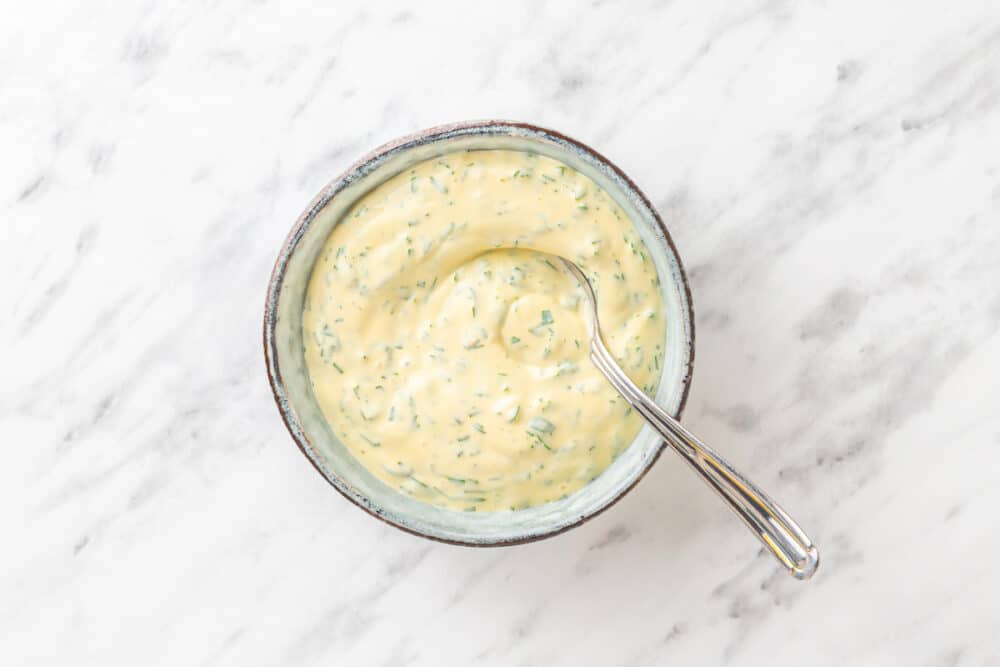 mayonnaise dipping sauce with fresh dill on white marble.