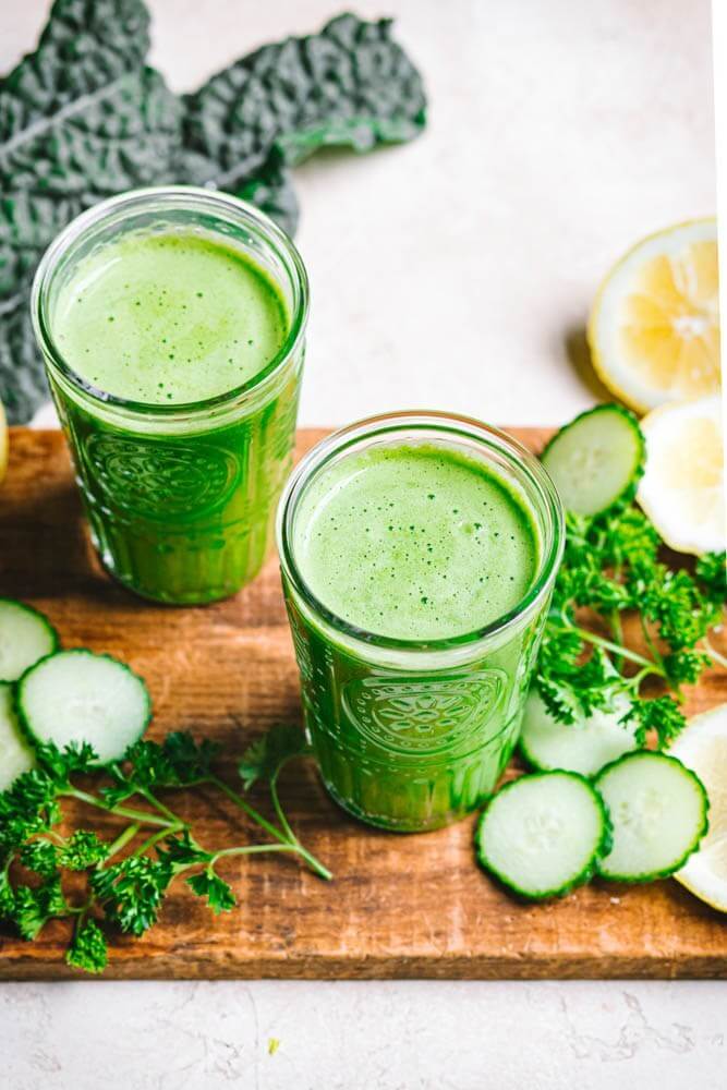 green-detox-juice-in-clear-glasses-on-a-wooden-board-with-ingredients-around