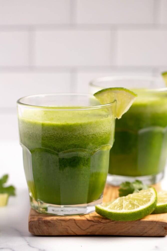 tropical-green-juice-in-glass-cups-with-a-lime-wedge-on-the-rim-and-on-a-wooden-board