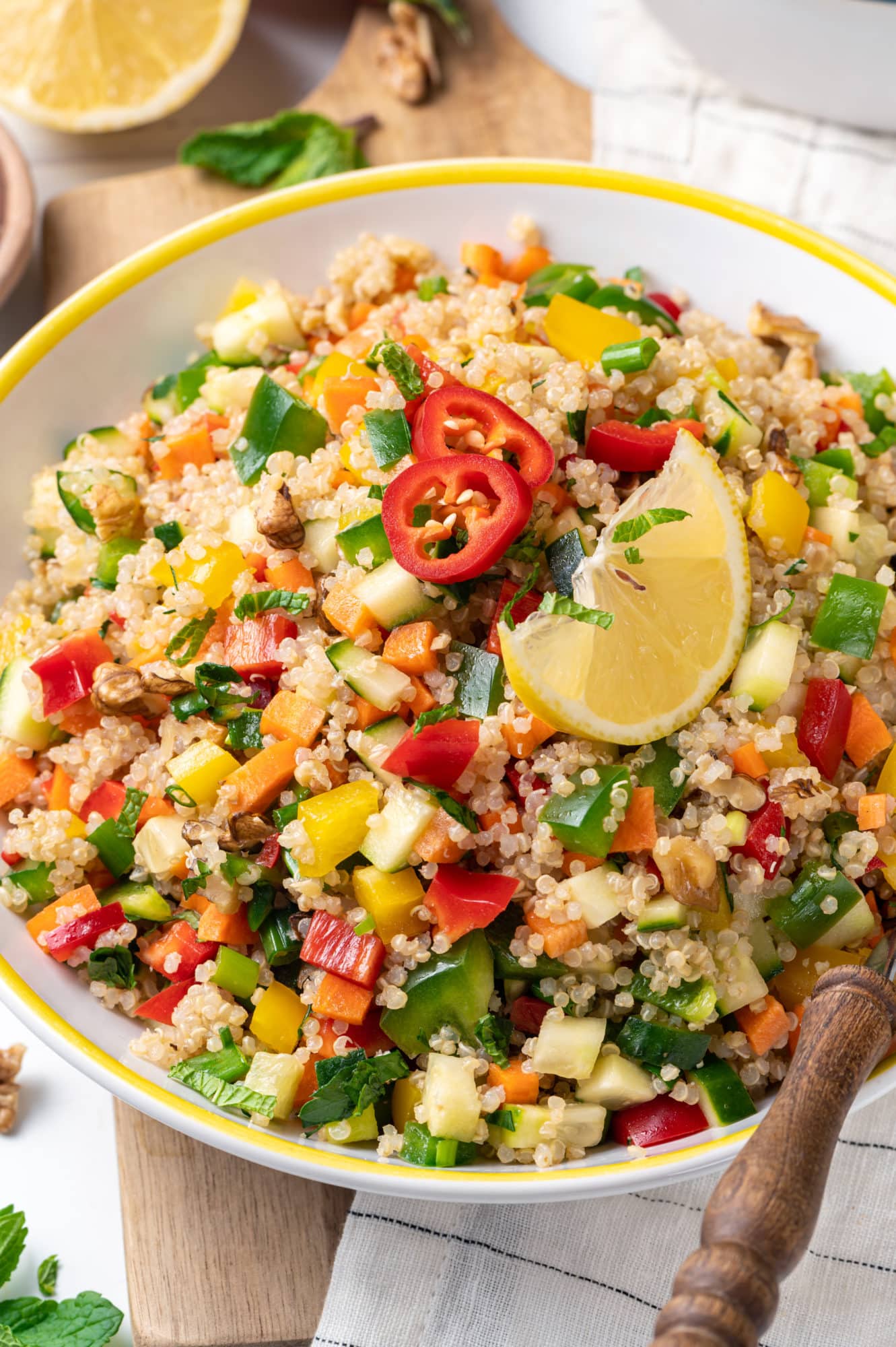 Fresh and Healthy Quinoa Salad with a Simple Vinaigrette close up of a quinoa and vegetable salad in a white bowl with a yellow rim.