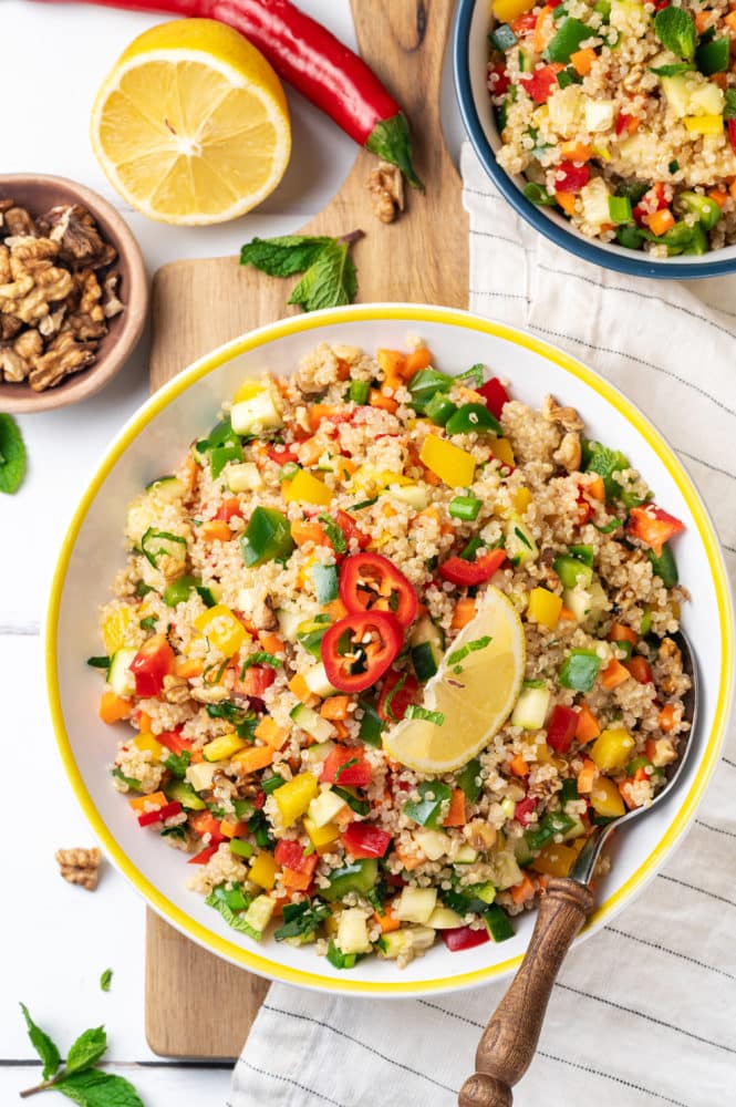 quinoa-salad-in-a-yellow-white-bowl-with-a-spoon-and-with-a-towel-on-the-side