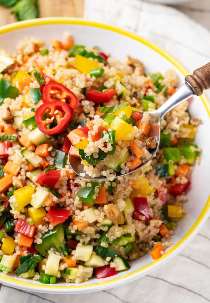 quinoa-salad-in-a-yellow-white-bowl-with-a-spoon-and-with-a-towel-on-the-side