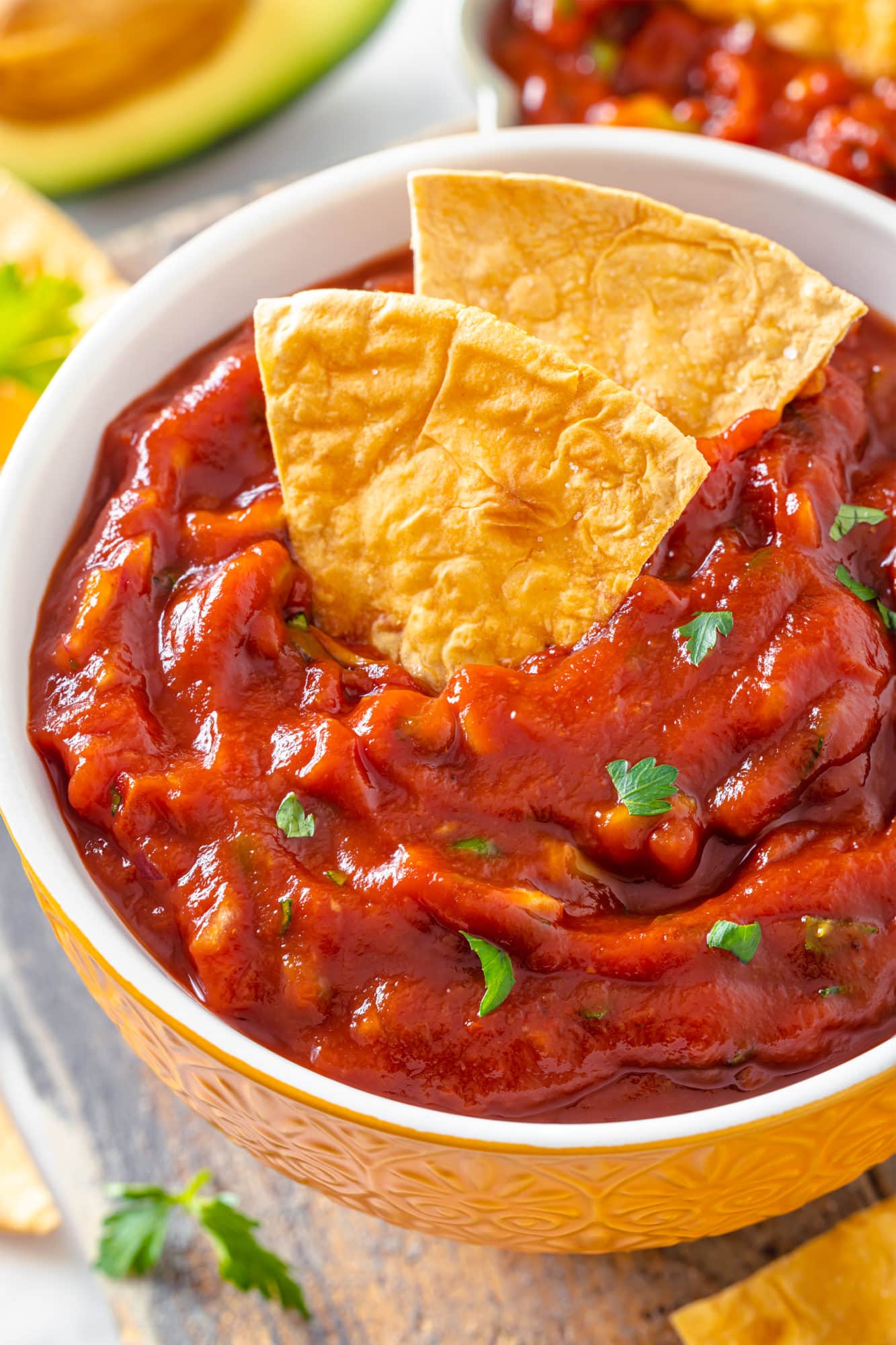 a close up of salsa in a bowl with chips in the salsa.