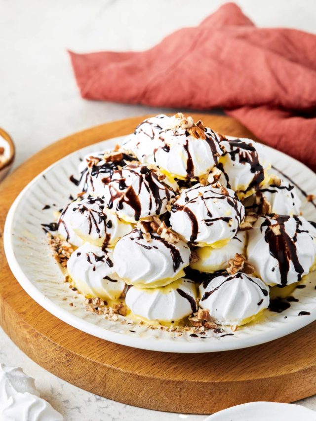 meringue pyramid on a white plate on a wooden board with a red towel in the background.