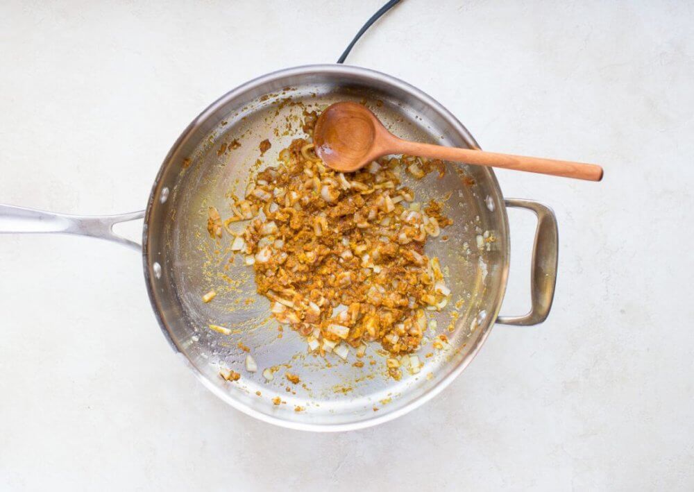 shallots-garlic-and-ginger-sauteing-in-a-skillet-with-a-wooden-spoon
