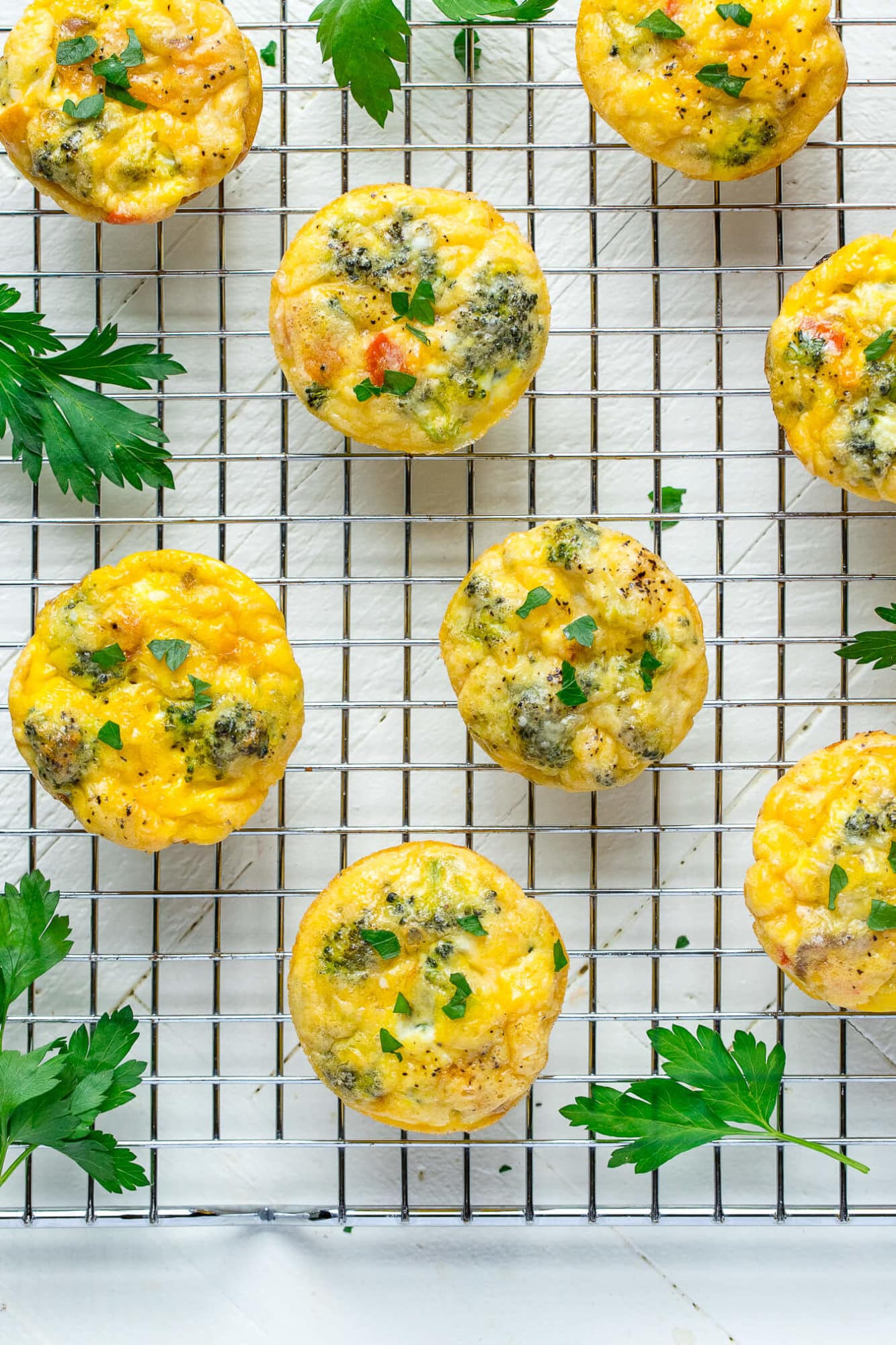 Frittata egg muffins on a wire rack with parsley around. 