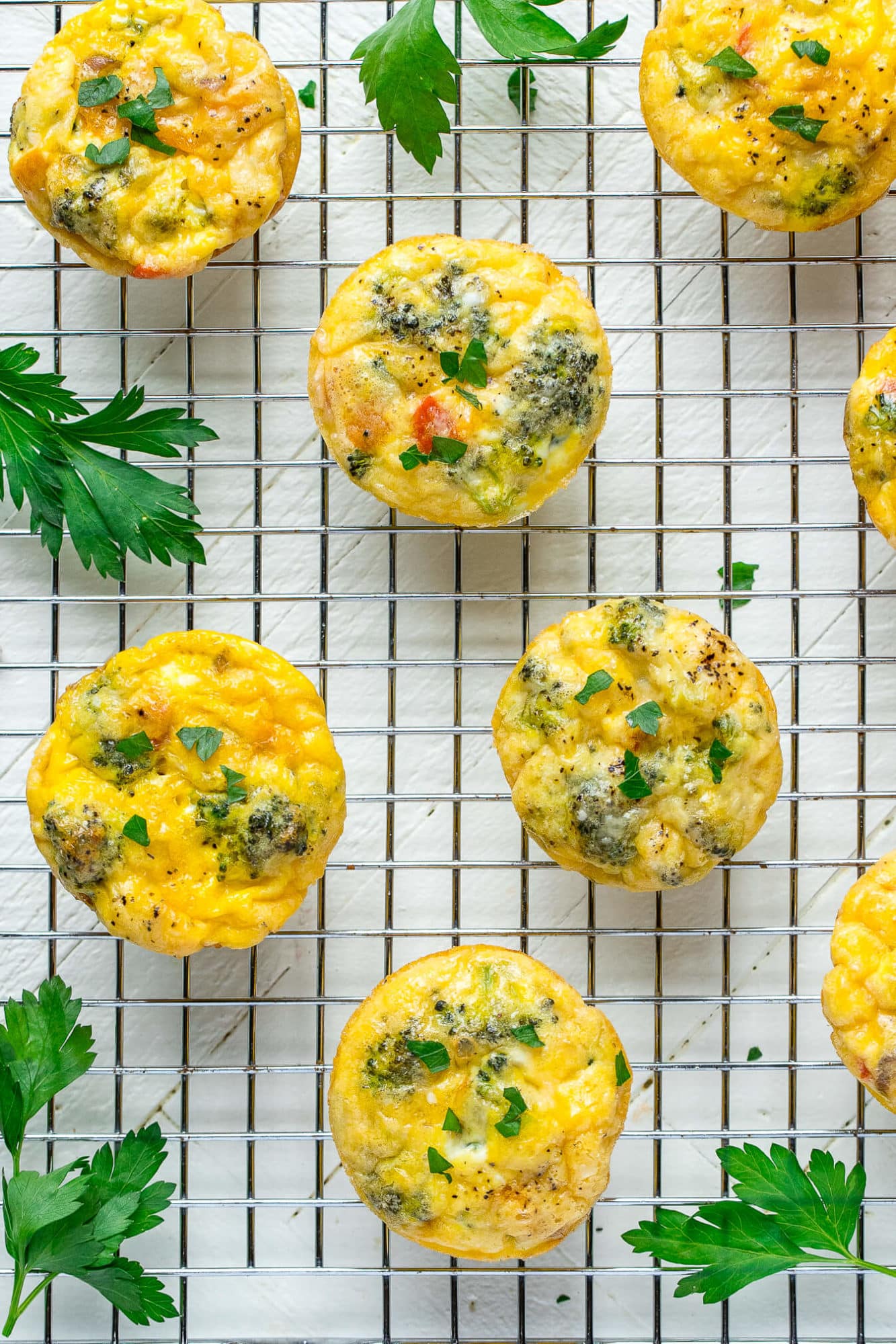 Frittata muffins on a wire rack with parsley around.