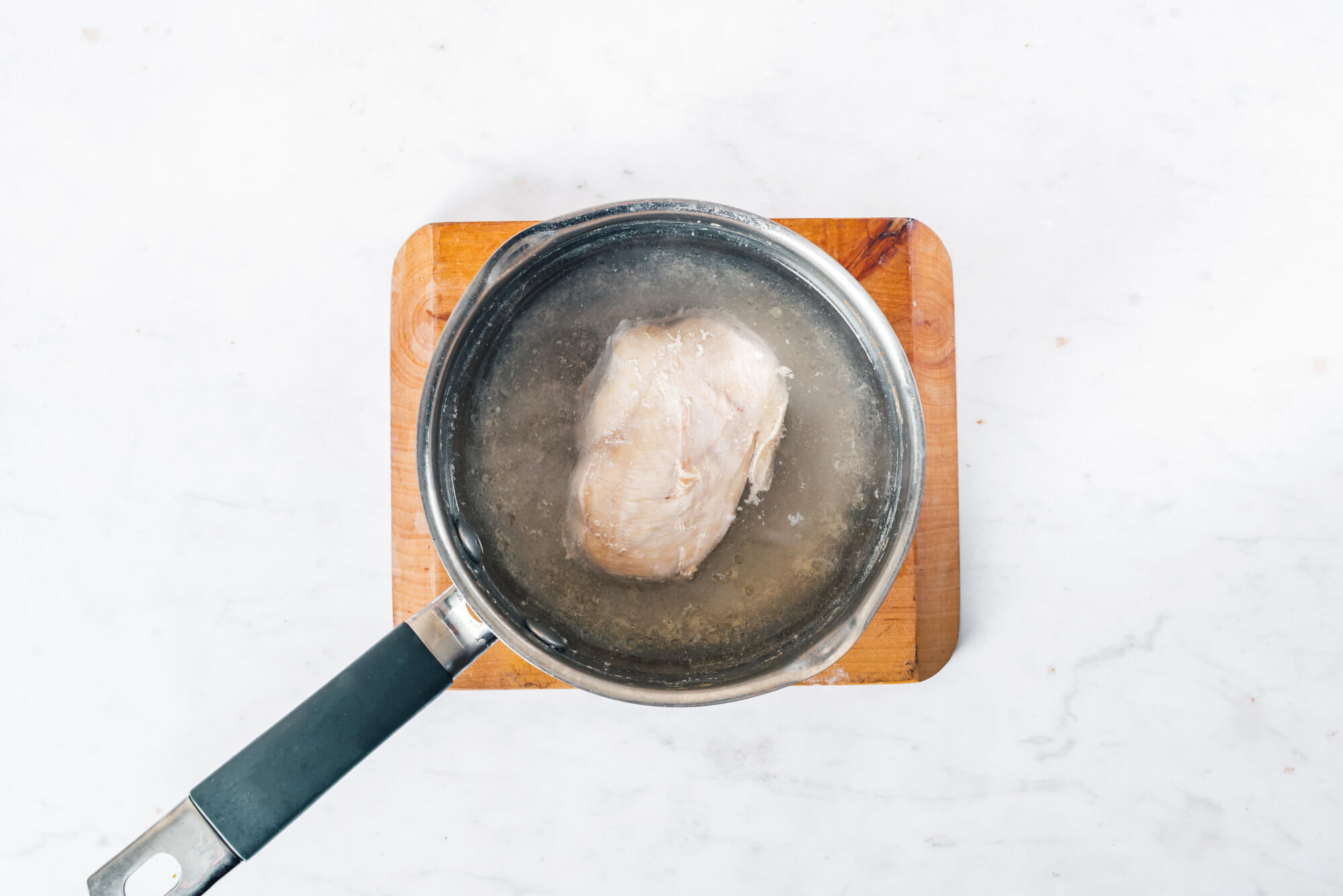 boiling chicken breast in saucepan. 