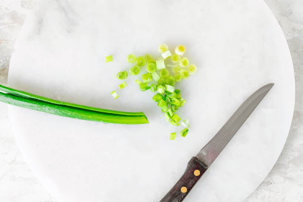 green-onion-chopped-on-a-marble-board-with-a-knife-on-the-side