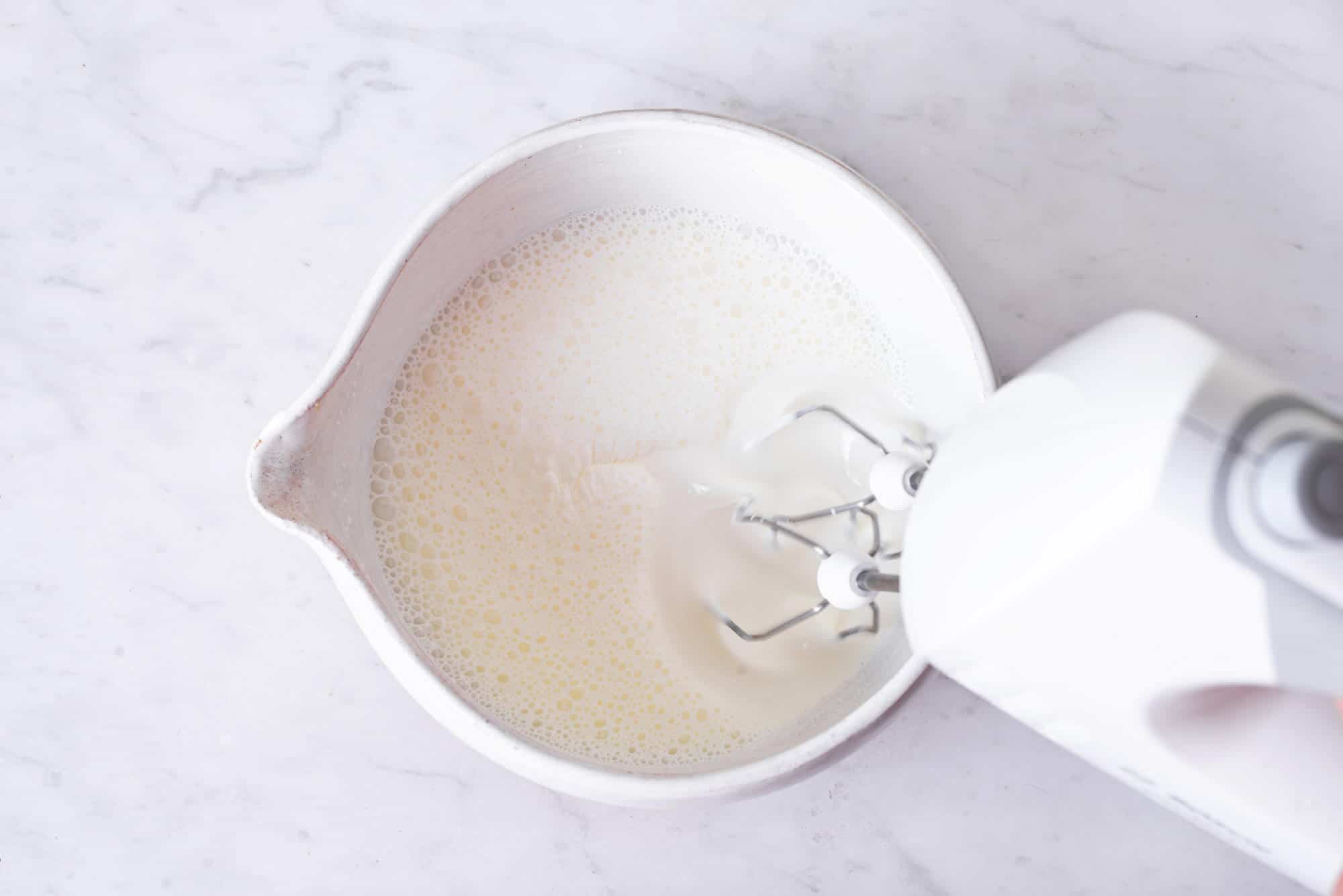 heavy-cream-whipping-in-a-white-bowl-with-hand-mixers