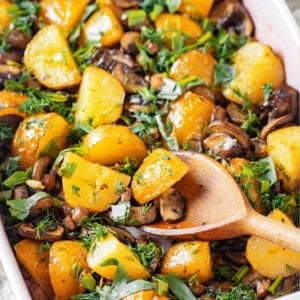 A dish with roasted potatoes and mushrooms in it.