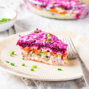 herring-salad-piece-on-a-beige-plate-on-a-white-towel-with-a-fork