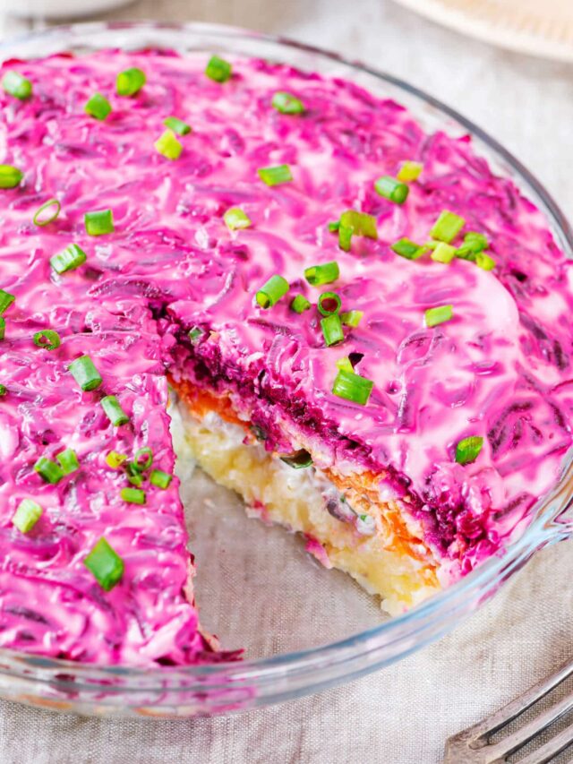 herring salad in a glass dish with one slice missing.