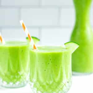 morning-green-smoothie-in-clear-cup-with-cucumber-wedge-and-striped-straw