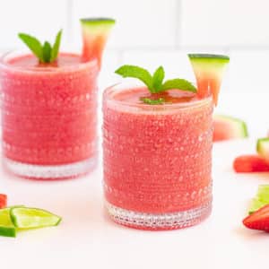 watermelon-strawberry-cooler-in-glasses-with-mint-and-watermelon-wedges-on-top-and-with-fruits-scattered-around