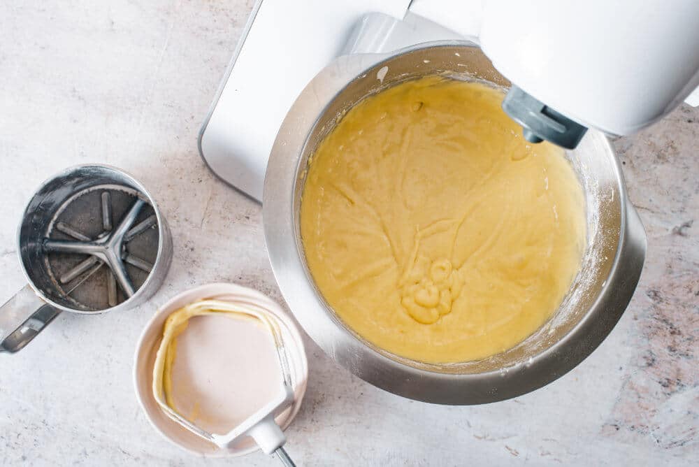 vanilla-cake-batter-in-a-stand-mixer-with-a-sifter-and-a-bowl-on-the-side
