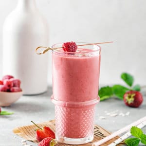berry-smoothie-in-a-glass-with-raspberries-and-strawberries-around-and-straws