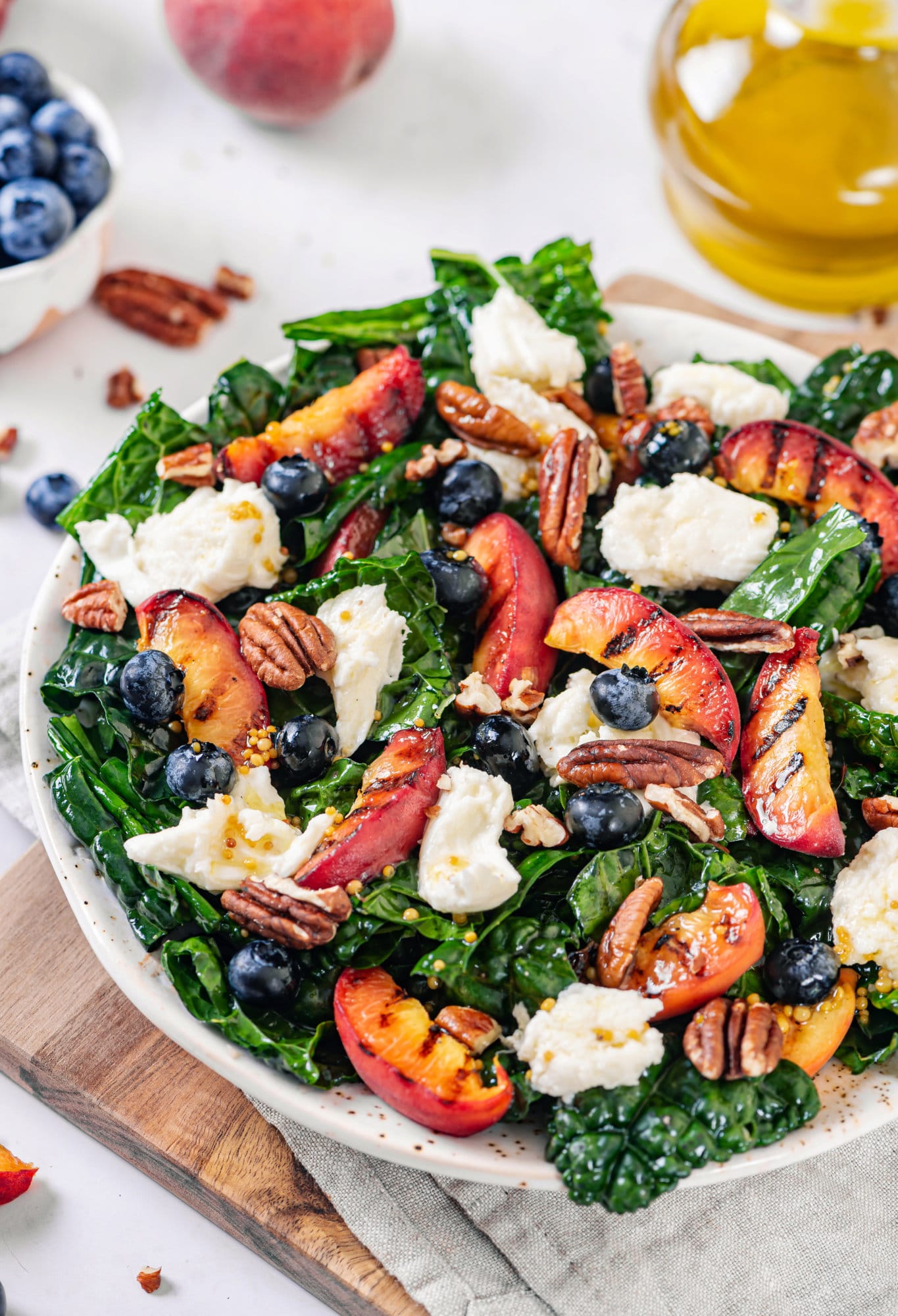 Grilled peaches atop kale in a salad with mozzarella, blueberries, and walnuts.