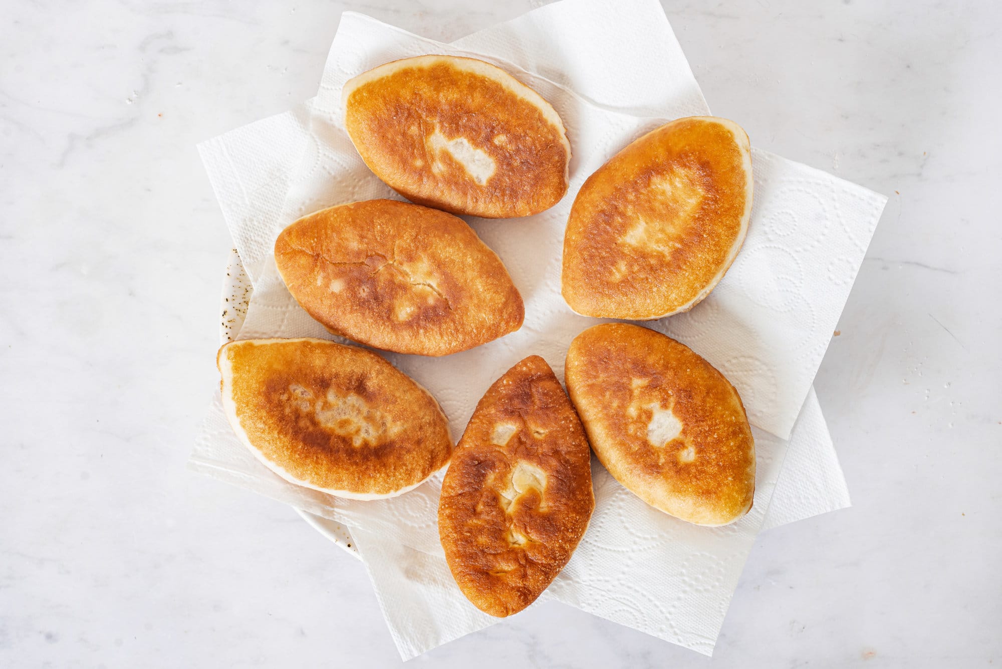 cooked-piroshki-on-white-paper-towels-on-a-plate