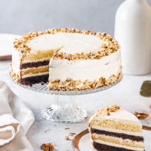 zebra-cake-on-a-cake-stand-with-one-slice-on-a-plate-with-a-towel-on-the-side