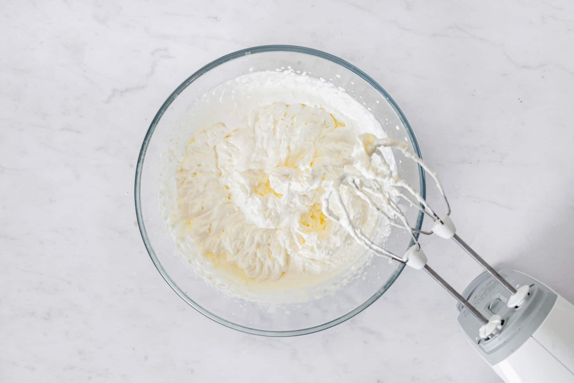 cheesecake-filling-in-a-clear-bowl-with-a-hand-mixer