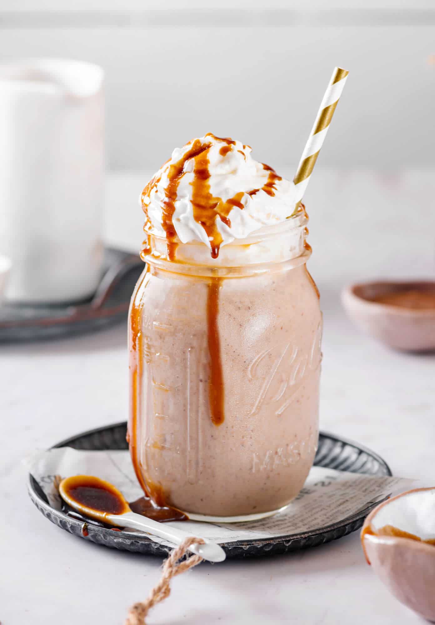 healthy caramel smoothie in a mason jar, with cream and caramel drizzle. 