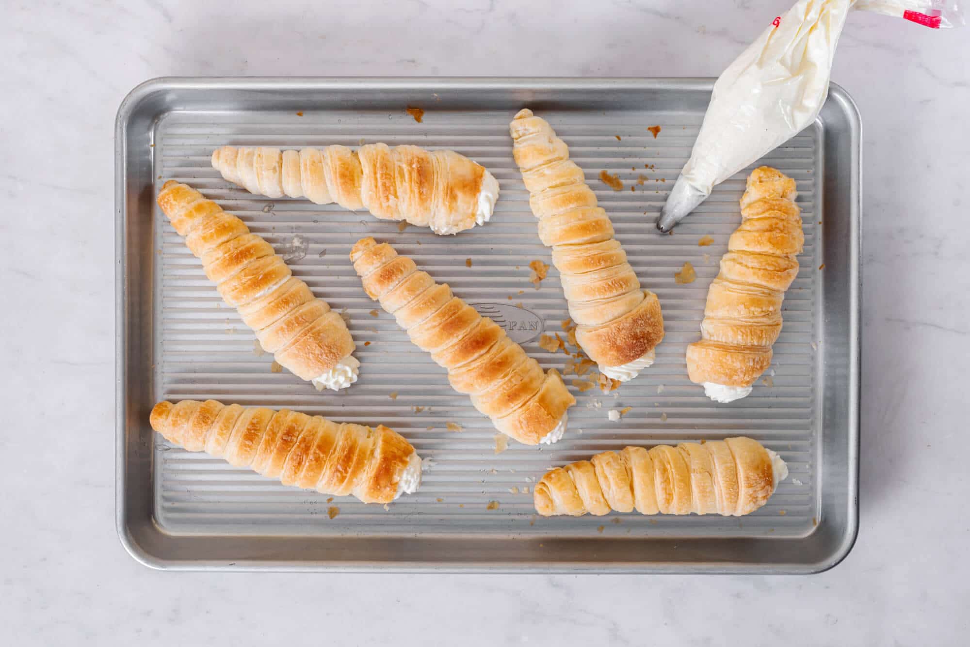 Cream horns on a baking tray freshly filled.