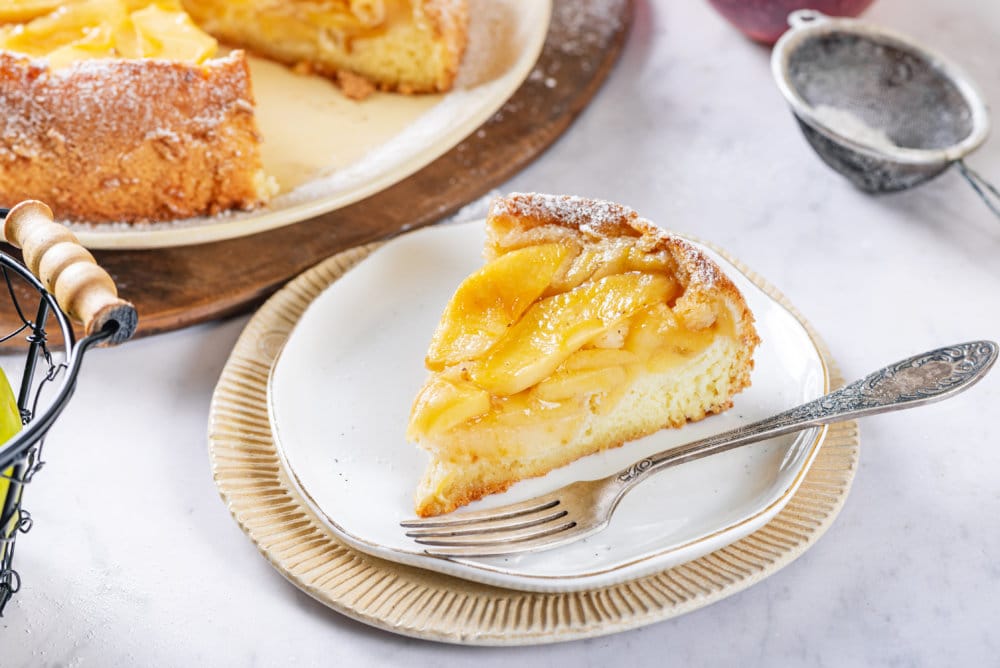 a slice of apple cake on a white plate with a fork.