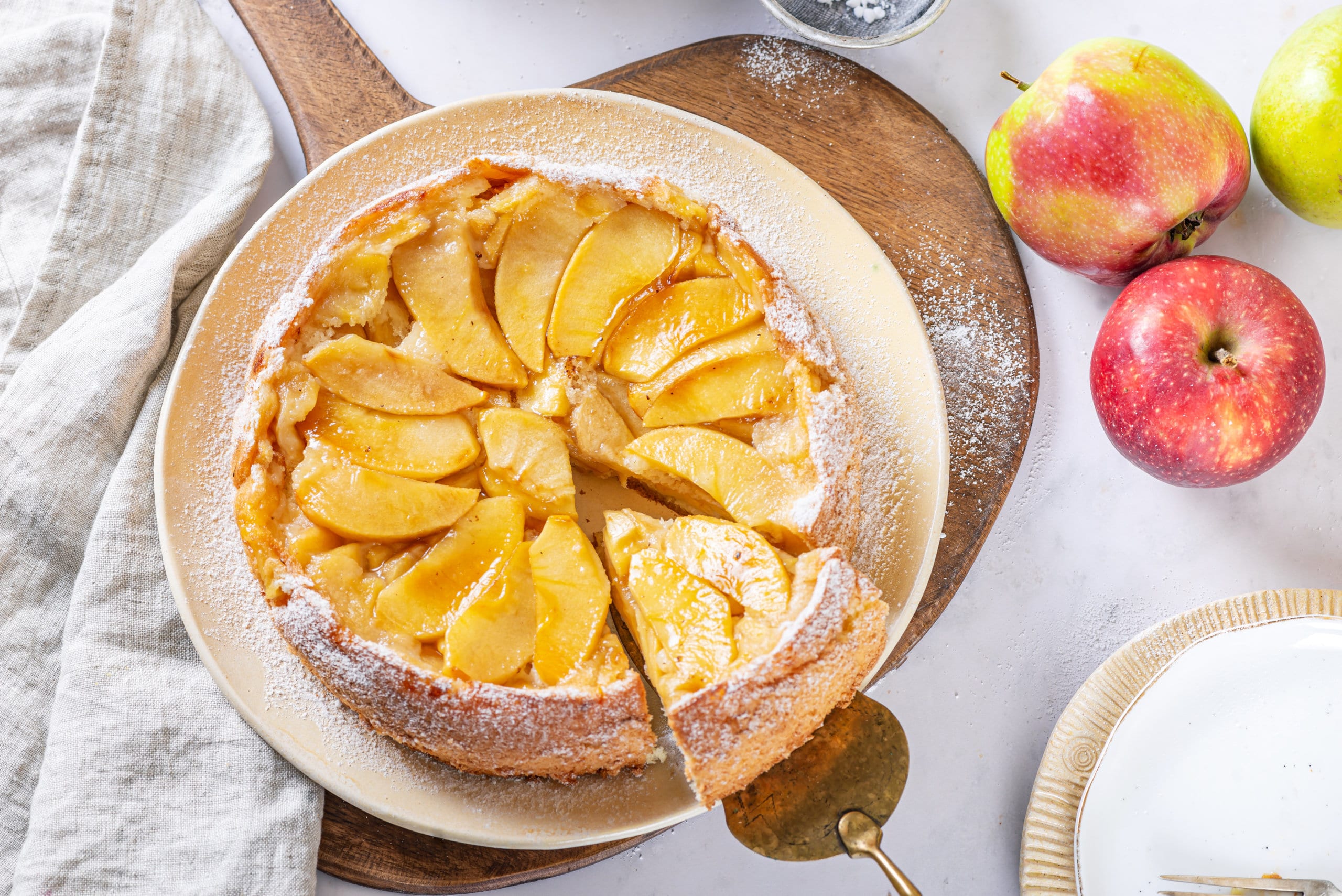 apple-cake-on-a-white-plate-on-a-wooden-board-with-a-spatula