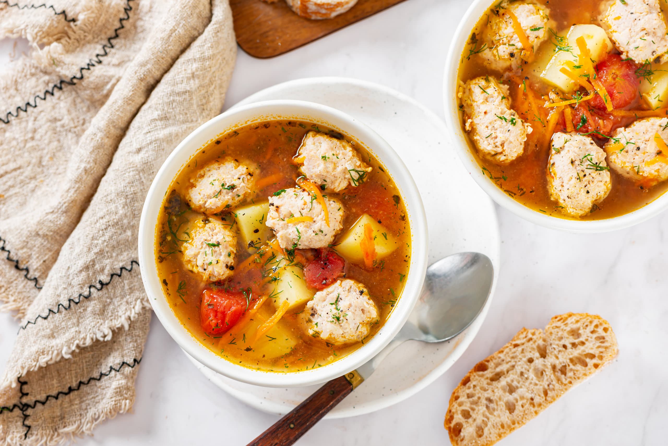 tomato-chicken-soup-in-a-white-bowl-on-a-white-plate-with-a-spoon