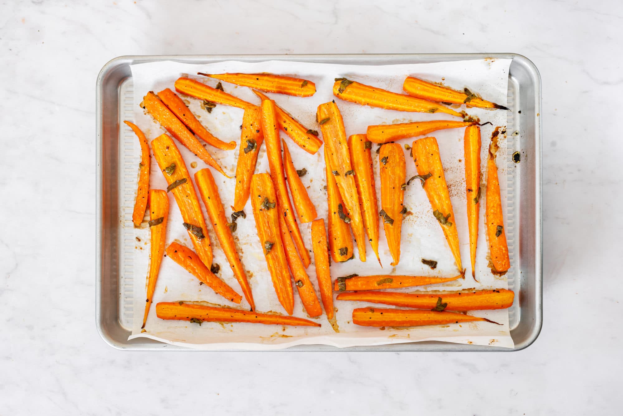 Roasted carrots atop a baking tray with parchment paper.