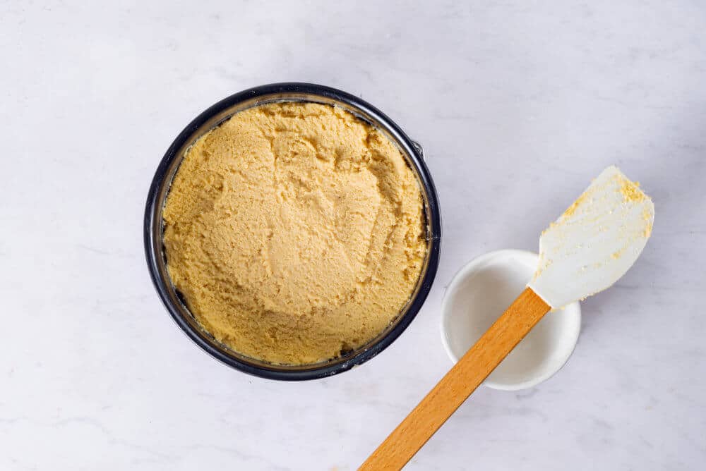 plum cake batter in a springform pan with a spatula on the side.